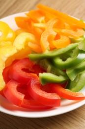Photo of Slices of fresh colorful bell peppers on wooden table, closeup