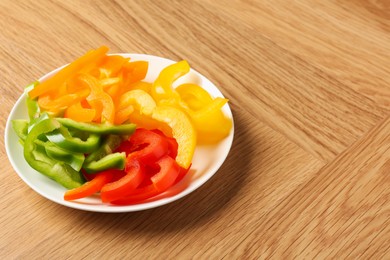 Photo of Slices of fresh colorful bell peppers on wooden table, closeup. Space for text