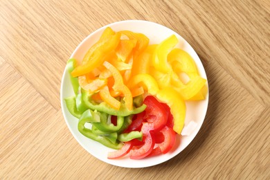 Photo of Slices of fresh colorful bell peppers on wooden table, top view