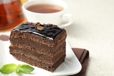 Photo of Piece of chocolate cake served with mint and tea on white table, closeup. Space for text