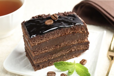 Photo of Piece of chocolate cake served with mint on white table, closeup