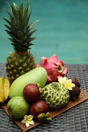Photo of Different tropical fruit on wicker table near swimming pool