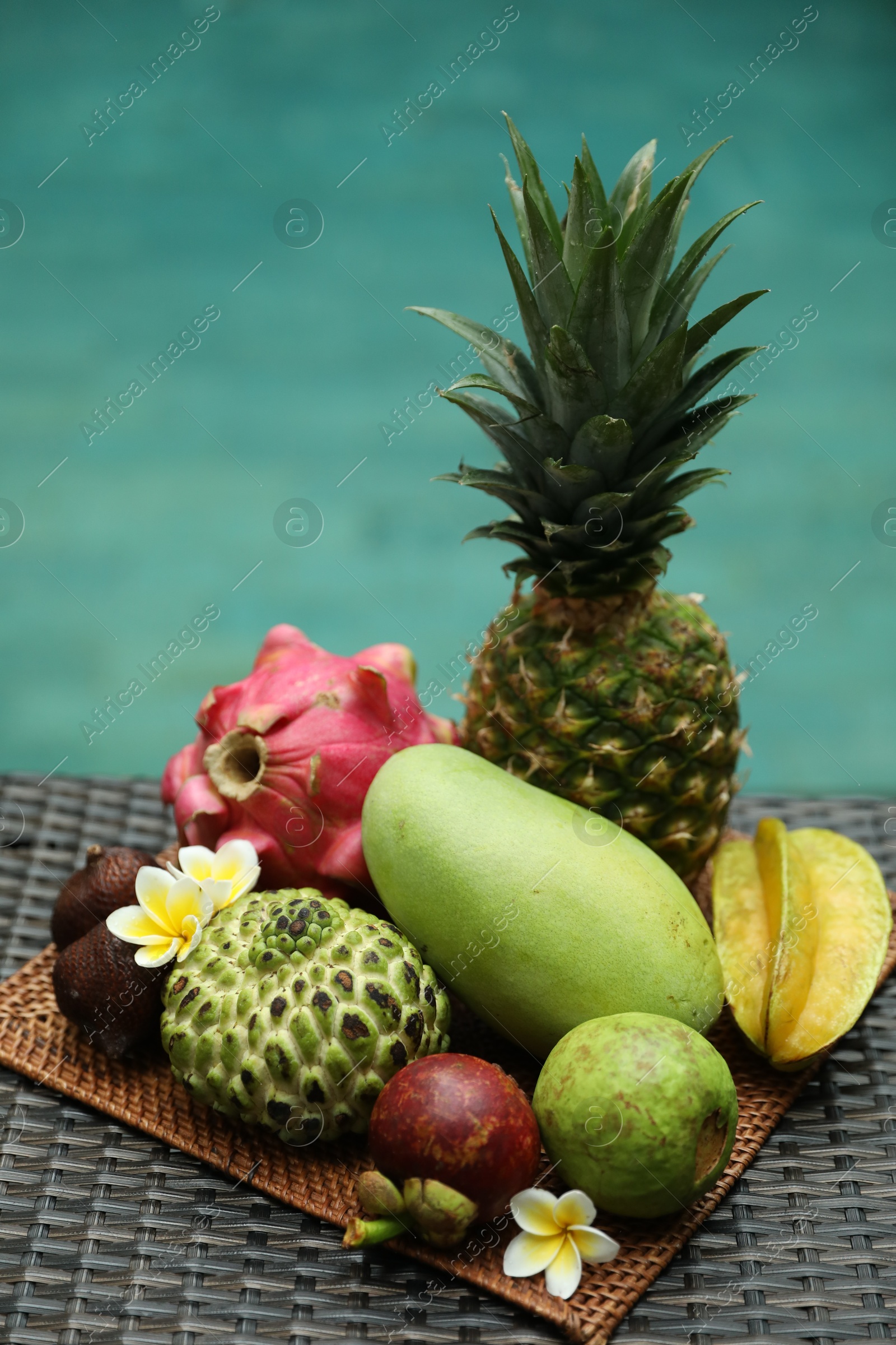 Different tropical fruit on wicker table near swimming pool Photo of Different tropical fruit on wicker table near swimming pool