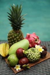 Photo of Different tropical fruit on wicker table near swimming pool