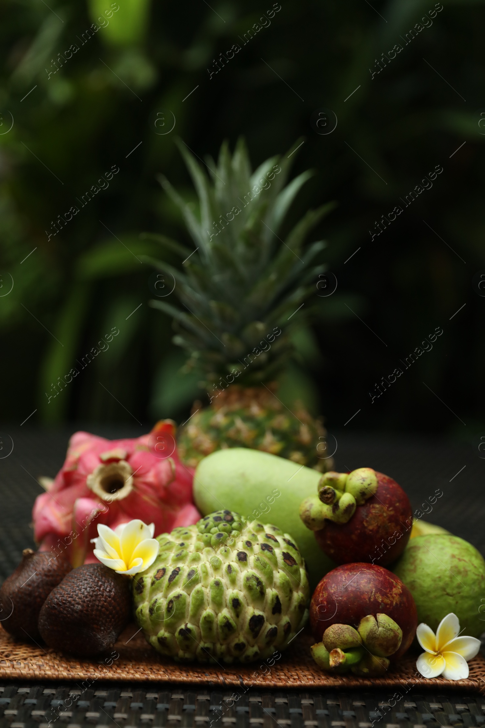 Photo of Different tropical fruit on wicker table outdoors