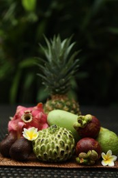Photo of Different tropical fruit on wicker table outdoors