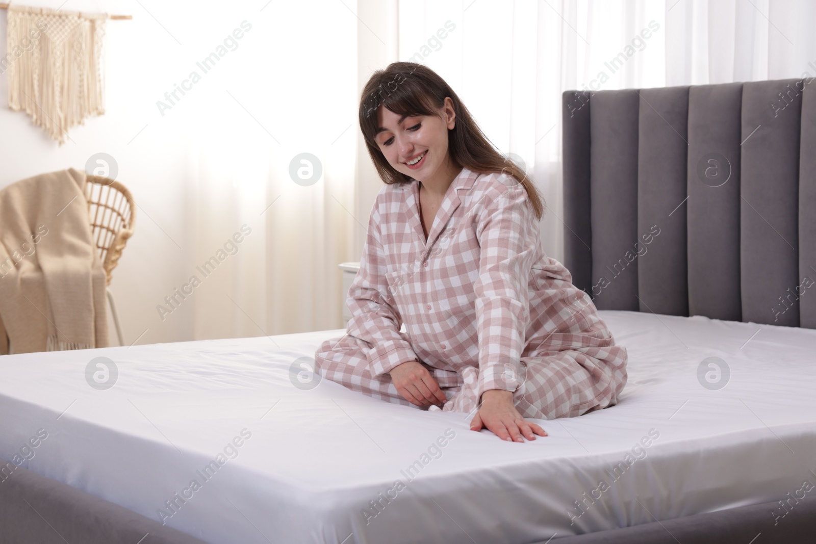 Photo of Beautiful woman sitting on soft mattress at home