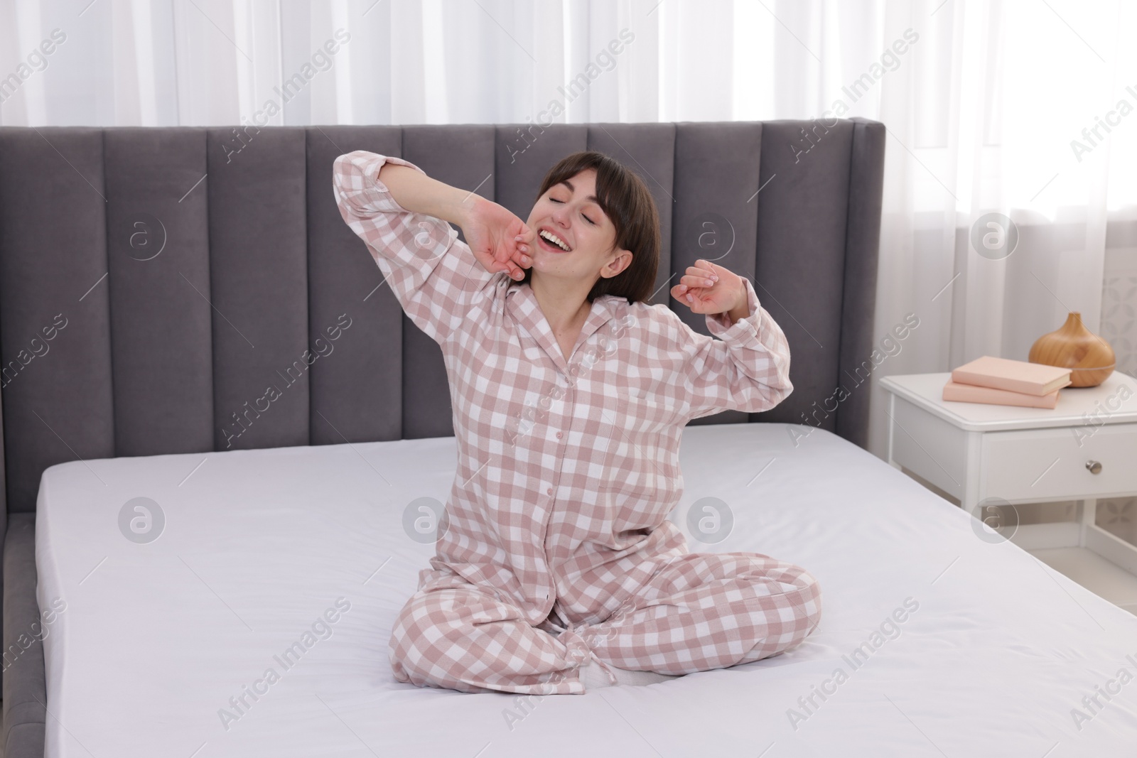 Sleepy woman yawning on bed at home Photo of Sleepy woman yawning on bed at home