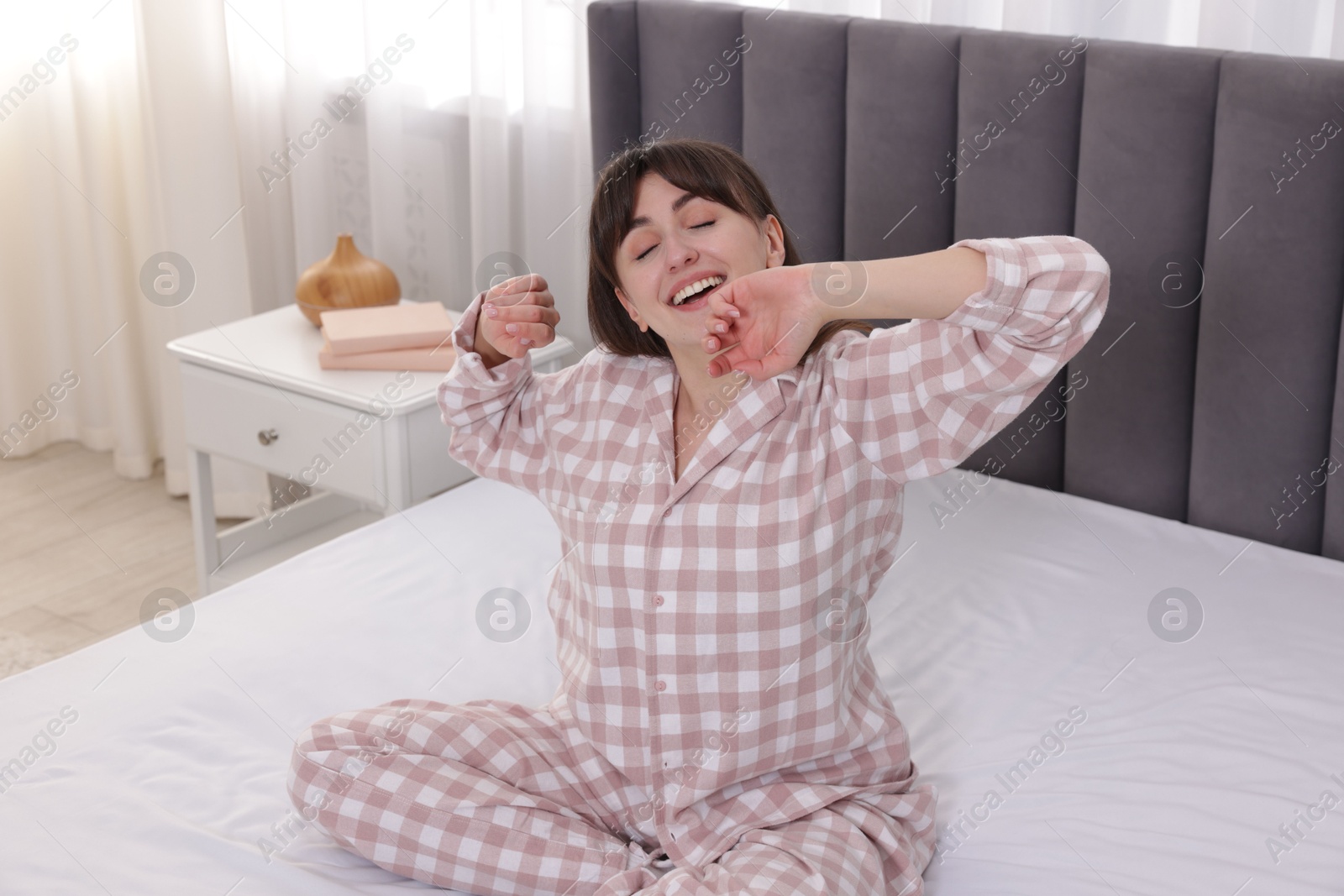 Sleepy woman yawning on bed at home Photo of Sleepy woman yawning on bed at home
