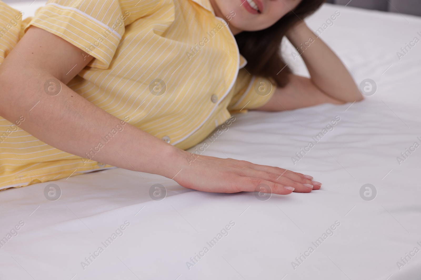 Woman touching soft mattress on bed indoors, closeup Photo of Woman touching soft mattress on bed indoors, closeup