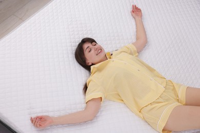 Photo of Beautiful woman lying on soft mattress at home, above view