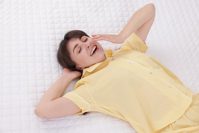 Photo of Sleepy woman yawning in bed at home, above view