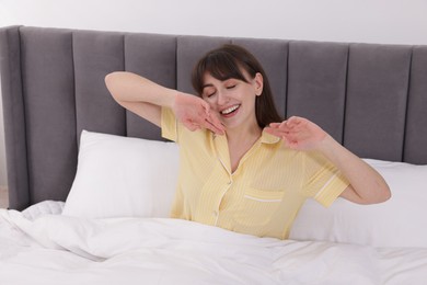 Photo of Sleepy woman yawning in bed at home