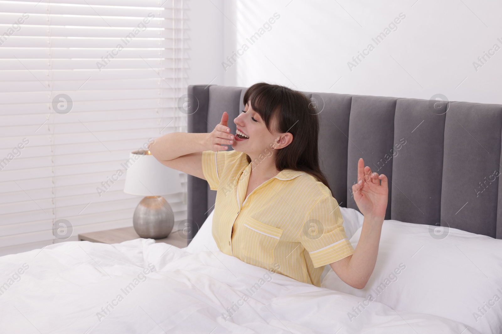 Sleepy woman yawning in bed at home Photo of Sleepy woman yawning in bed at home