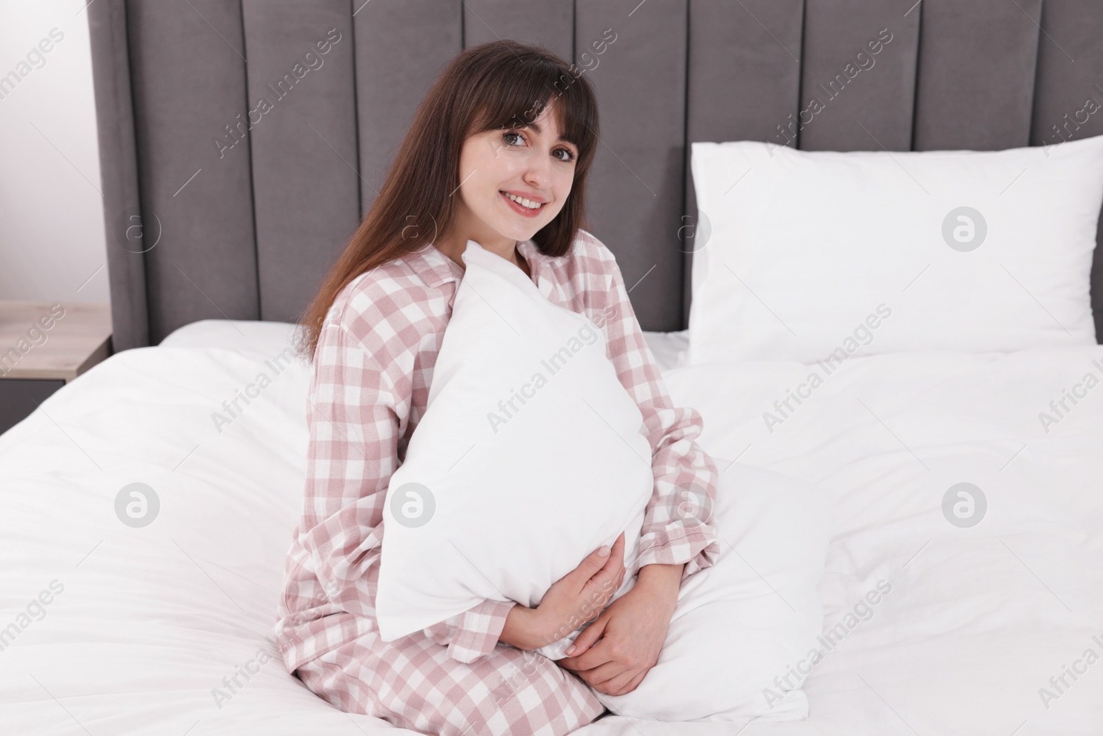 Beautiful woman with pillow on bed at home Photo of Beautiful woman with pillow on bed at home