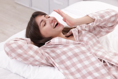 Photo of Sleepy woman yawning on bed at home