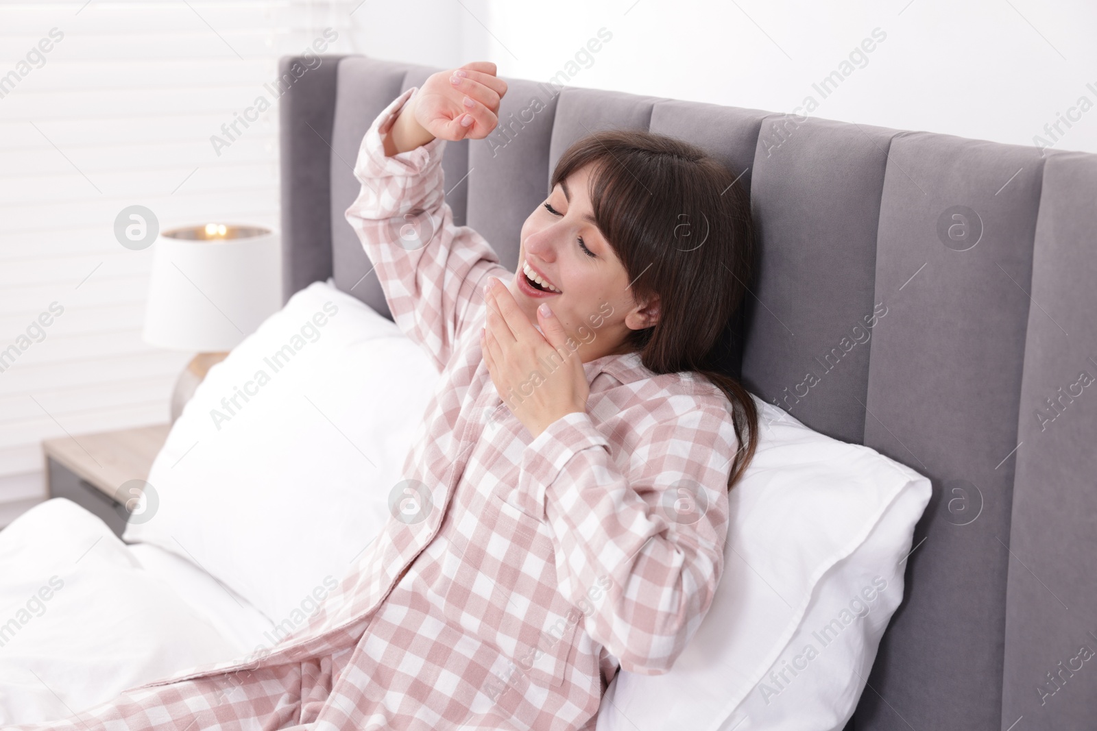 Sleepy woman yawning on bed at home Photo of Sleepy woman yawning on bed at home