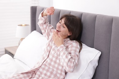 Photo of Sleepy woman yawning on bed at home