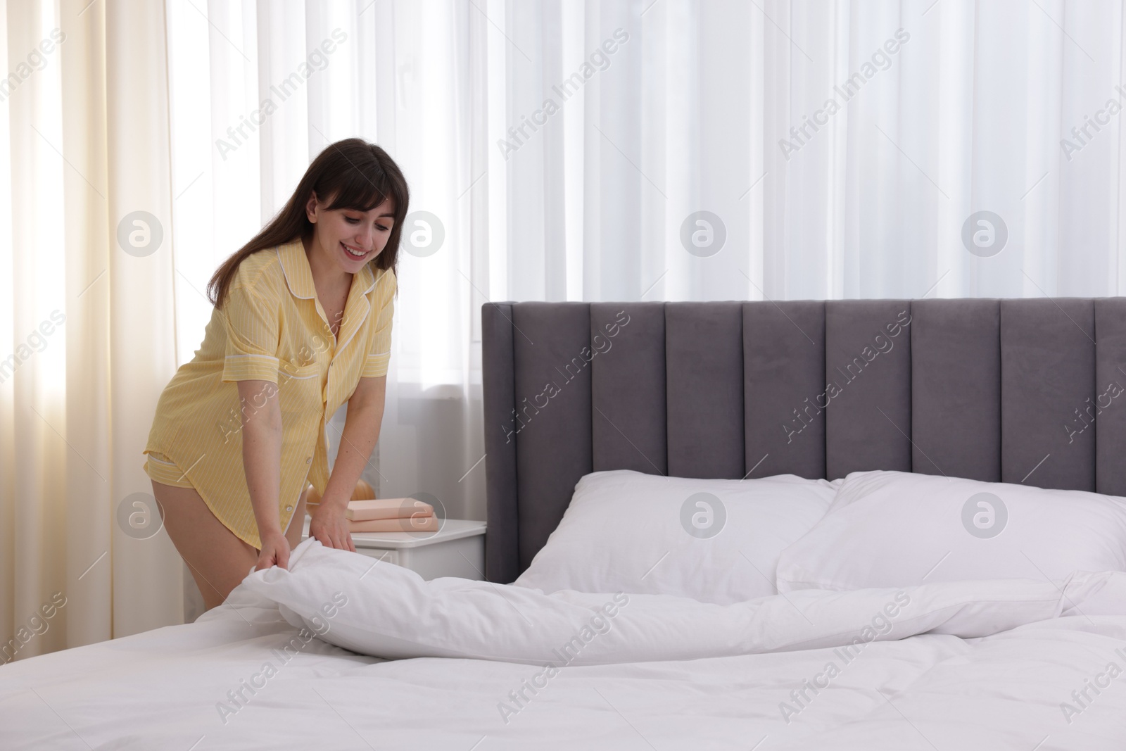 Beautiful young woman making bed at home Photo of Beautiful young woman making bed at home