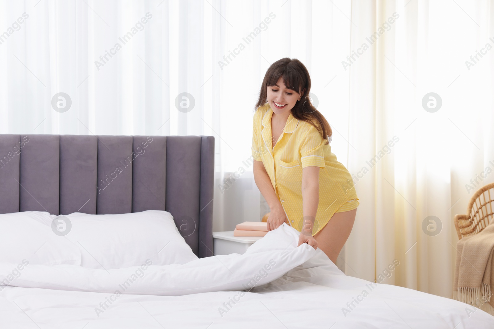 Beautiful young woman making bed at home Photo of Beautiful young woman making bed at home