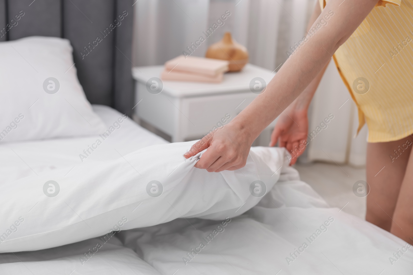 Woman making bed at home, closeup view Photo of Woman making bed at home, closeup view
