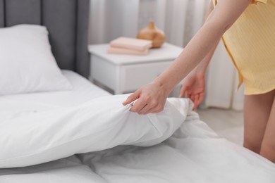 Photo of Woman making bed at home, closeup view