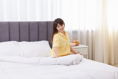 Photo of Beautiful young woman sitting on bed at home
