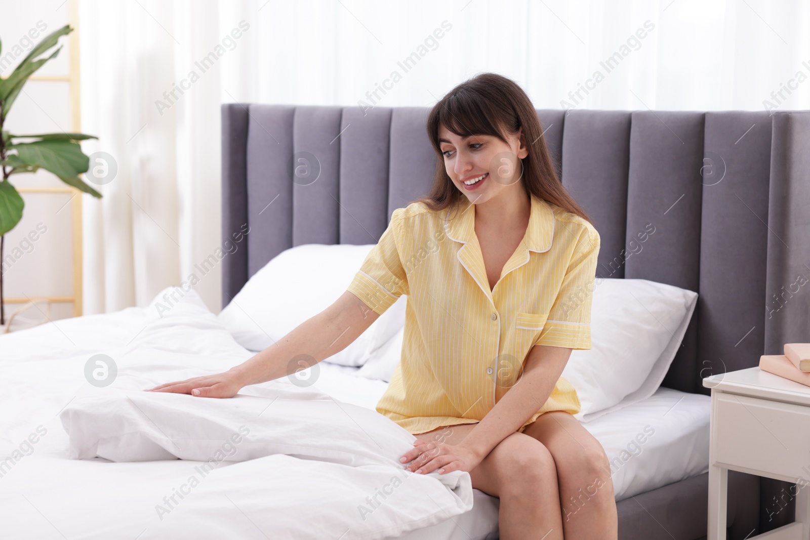 Beautiful young woman sitting on bed at home Photo of Beautiful young woman sitting on bed at home