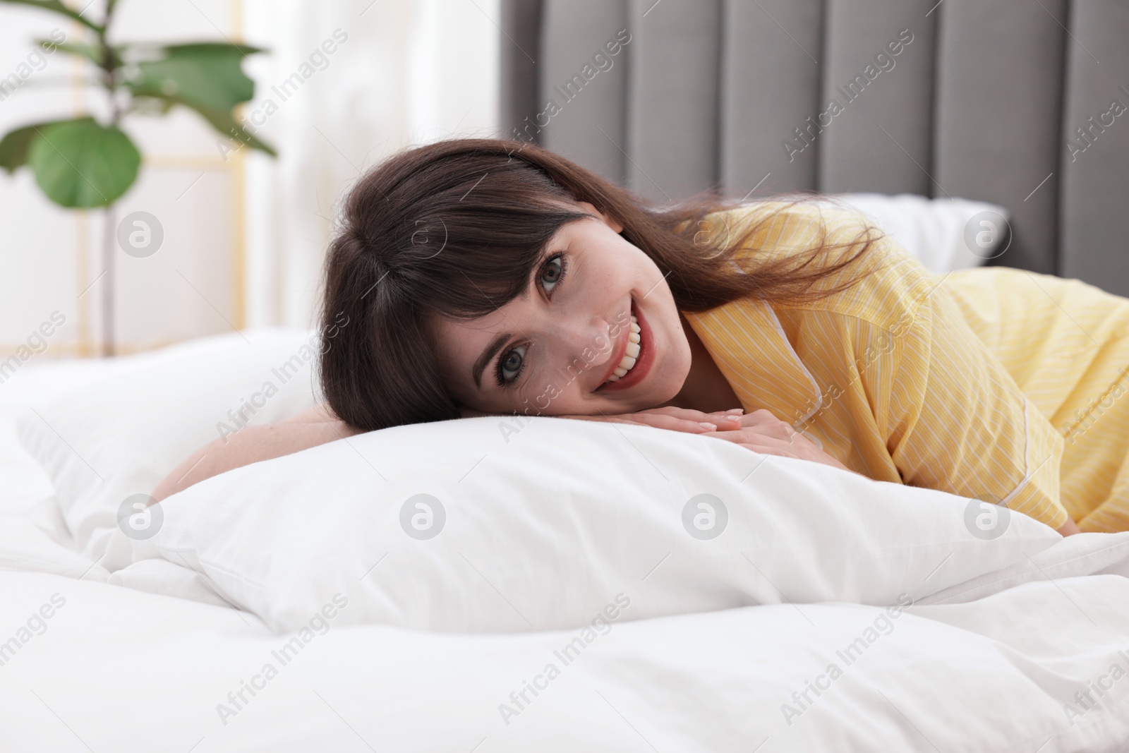 Smiling woman lying on bed at home Photo of Smiling woman lying on bed at home