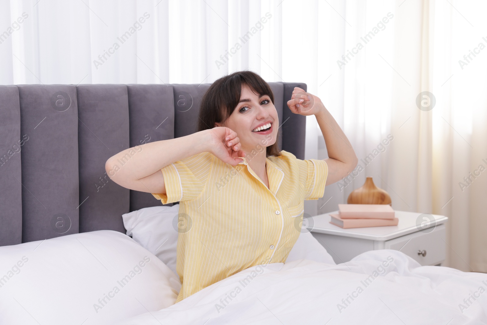 Smiling woman stretching in bed at home Photo of Smiling woman stretching in bed at home