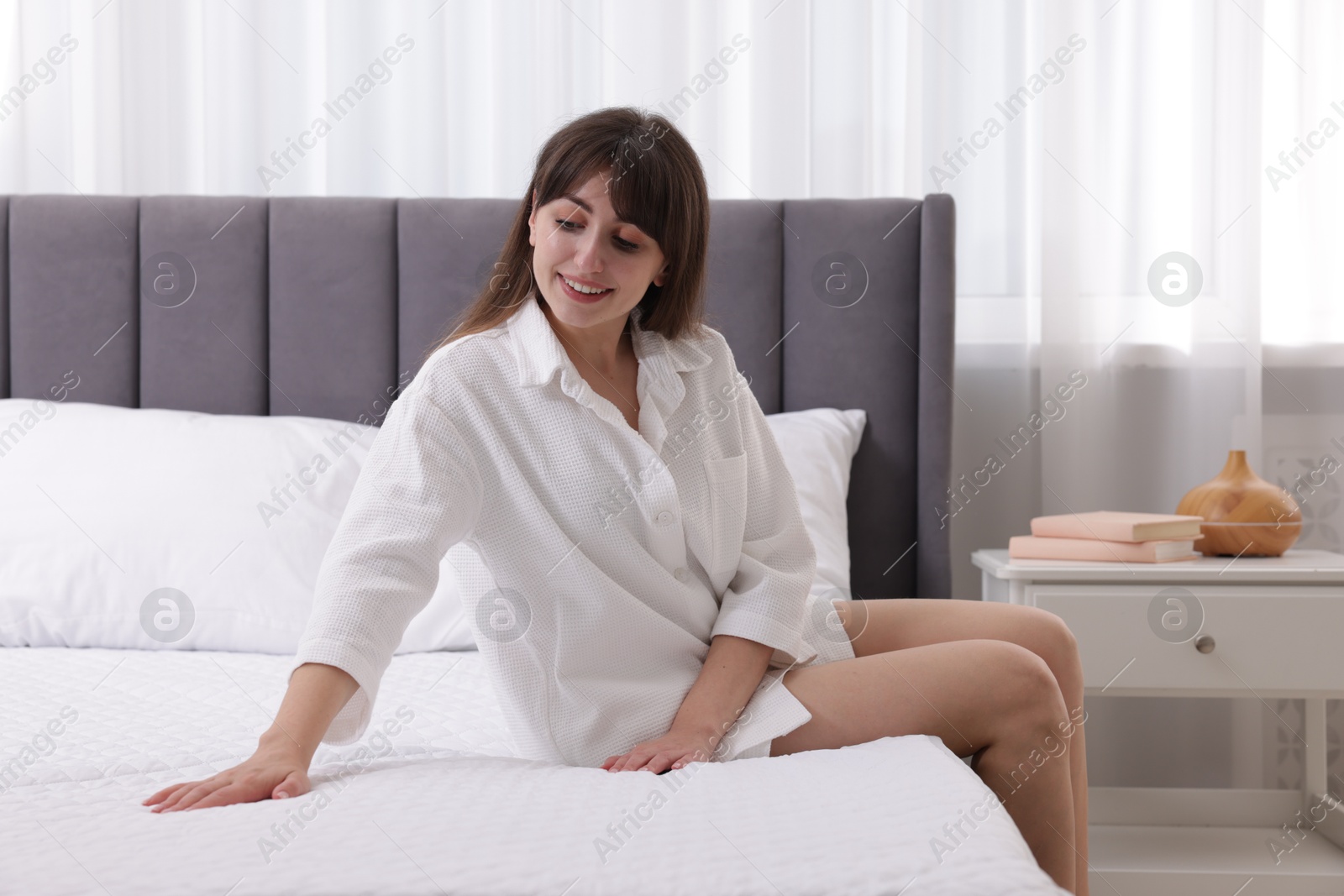 Beautiful woman sitting on soft mattress at home Photo of Beautiful woman sitting on soft mattress at home