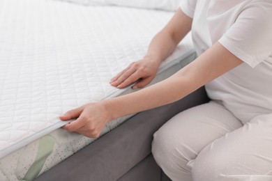 Photo of Woman putting cover on soft mattress at home, closeup