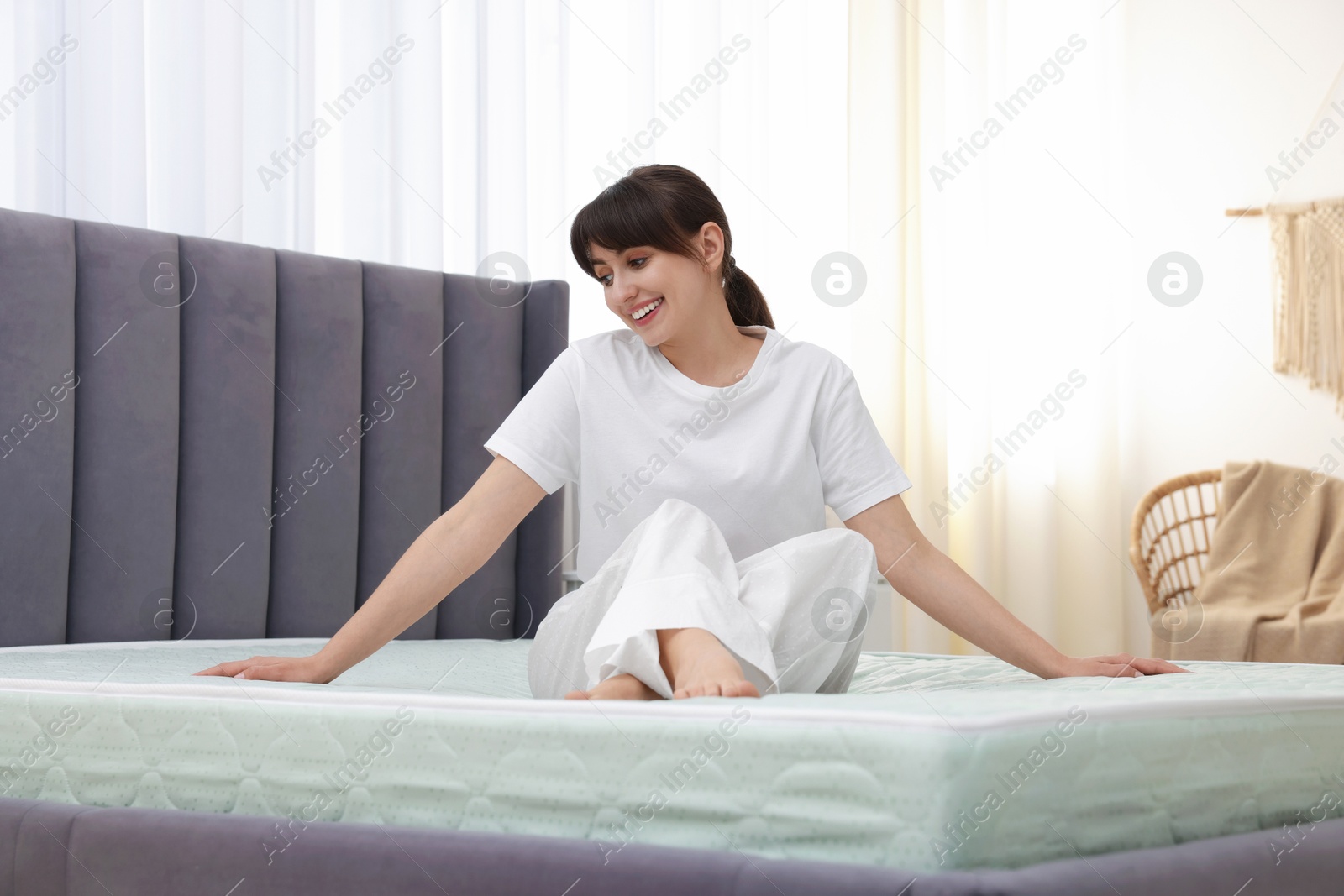 Beautiful woman sitting on soft mattress at home Photo of Beautiful woman sitting on soft mattress at home