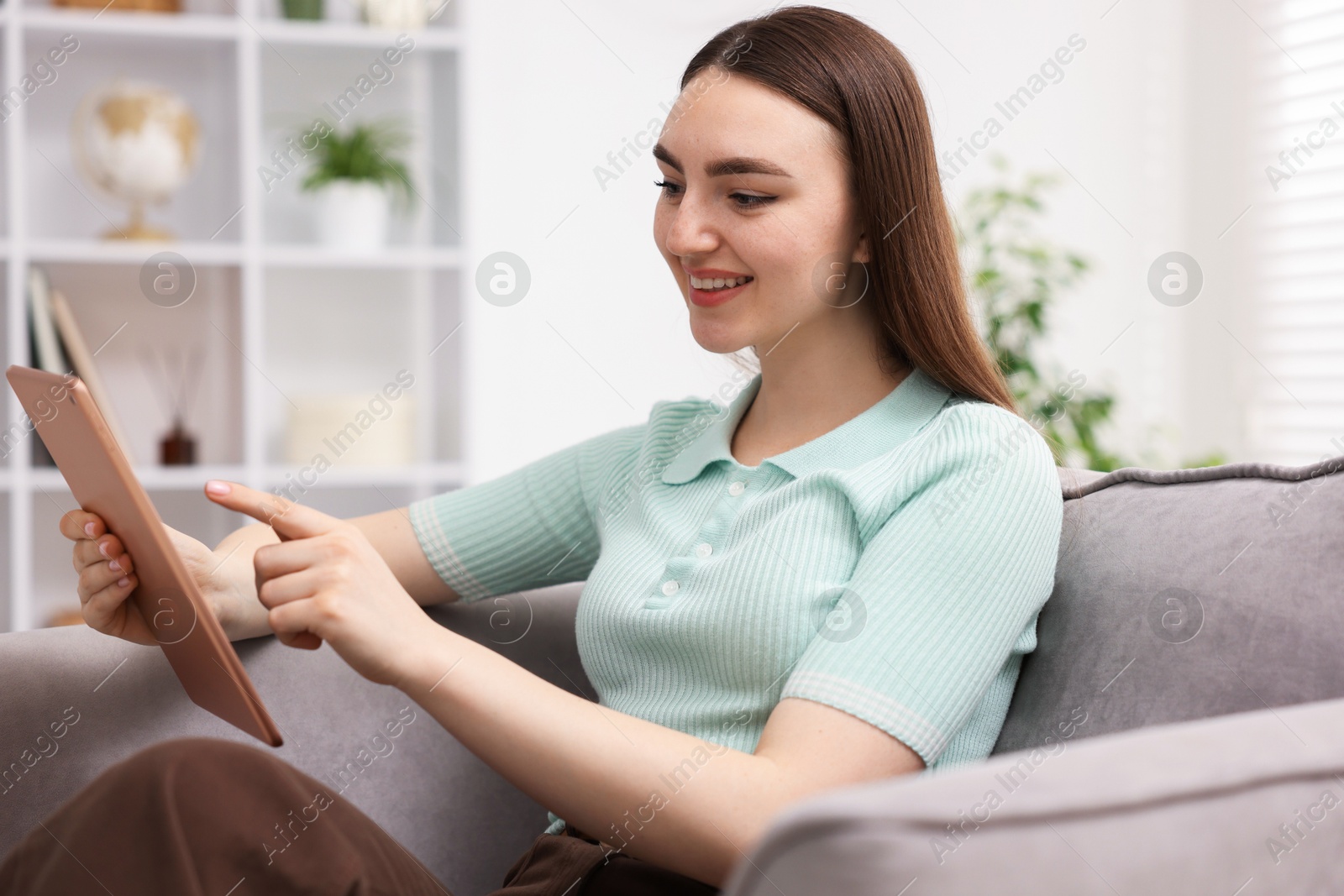 Young woman using modern tablet in armchair at home Photo of Young woman using modern tablet in armchair at home