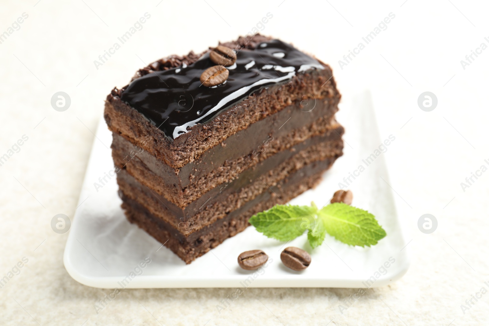 Photo of Piece of chocolate cake served with mint on white table, closeup