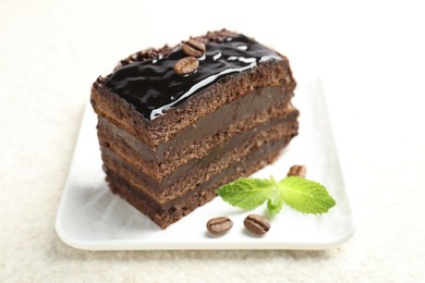 Photo of Piece of chocolate cake served with mint on white table, closeup