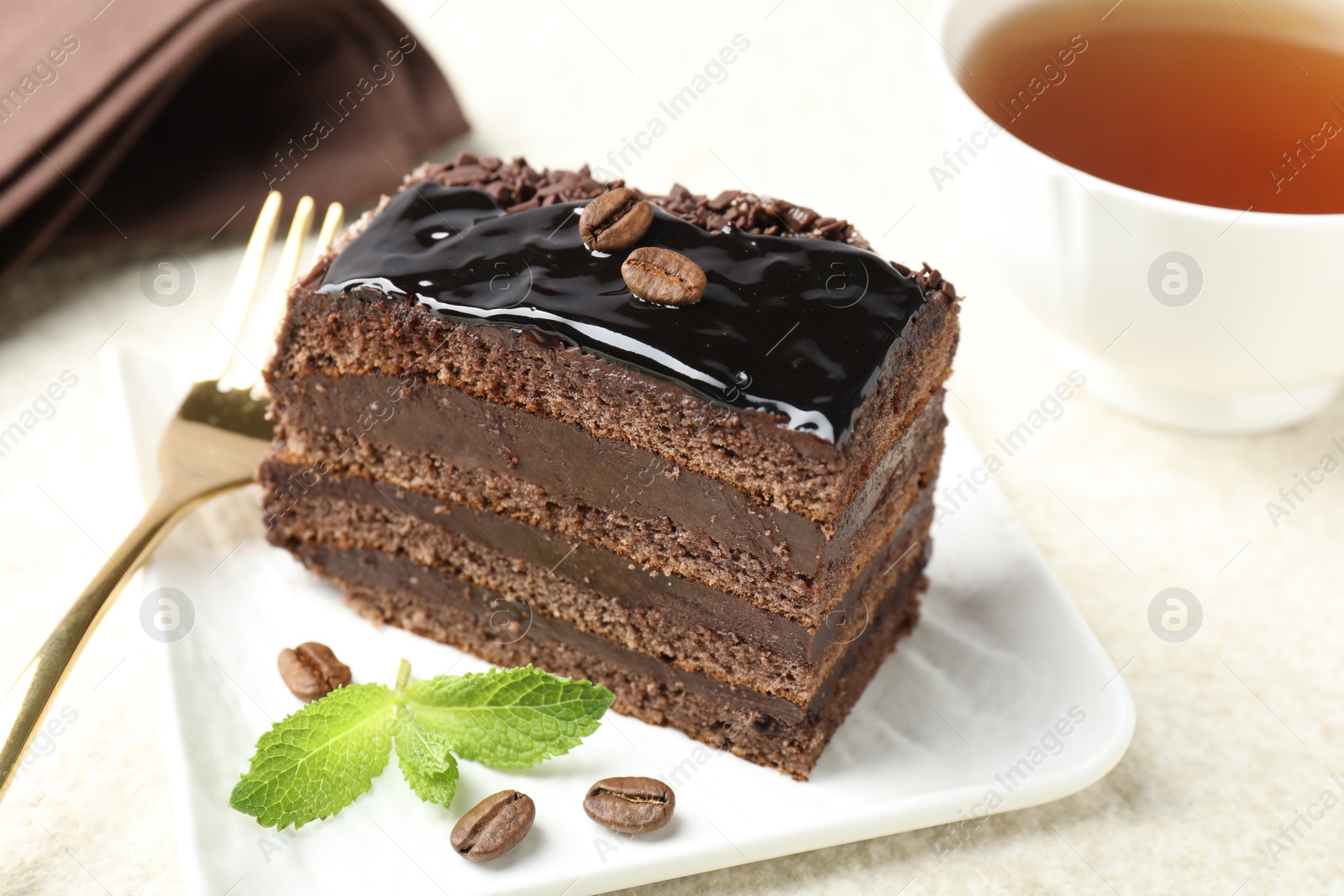 Photo of Piece of chocolate cake served with mint and fork on table, closeup