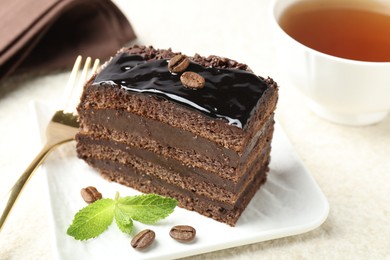 Photo of Piece of chocolate cake served with mint and fork on table, closeup