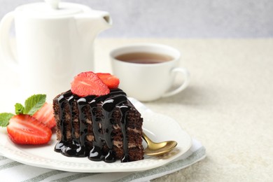 Photo of Piece of chocolate cake served with strawberries, tea and spoon on white table, closeup. Space for text