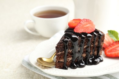 Photo of Piece of chocolate cake served with strawberries, tea and spoon on white table, closeup. Space for text