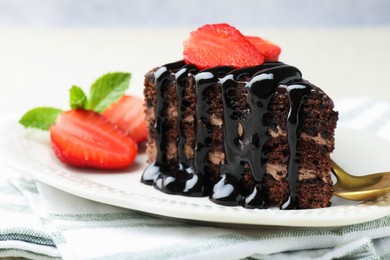 Photo of Piece of chocolate cake served with strawberries and spoon on table, closeup