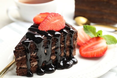 Photo of Piece of chocolate cake served with strawberries on table, closeup