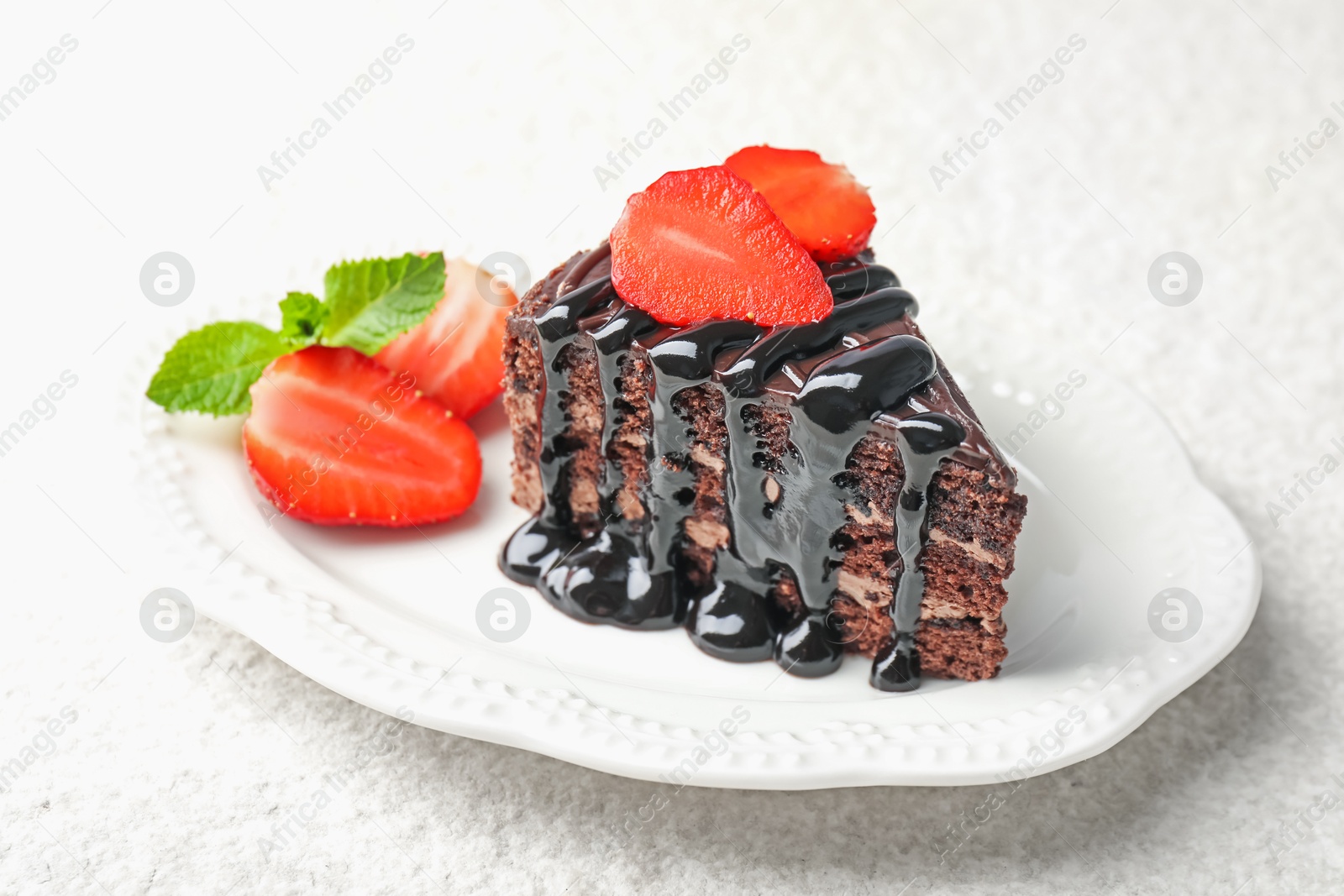 Photo of Piece of chocolate cake served with strawberries on white table, closeup