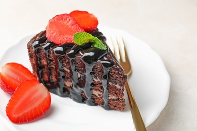 Photo of Piece of chocolate cake served with strawberries and fork on white table, closeup