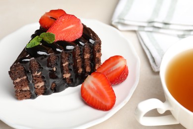 Photo of Piece of chocolate cake served with strawberries and tea on white table, closeup