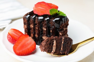 Photo of Piece of chocolate cake served with strawberries and spoon on white table, closeup