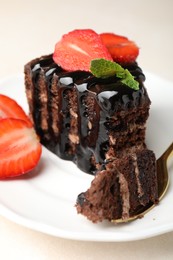 Photo of Piece of chocolate cake served with strawberries and spoon on white table, closeup