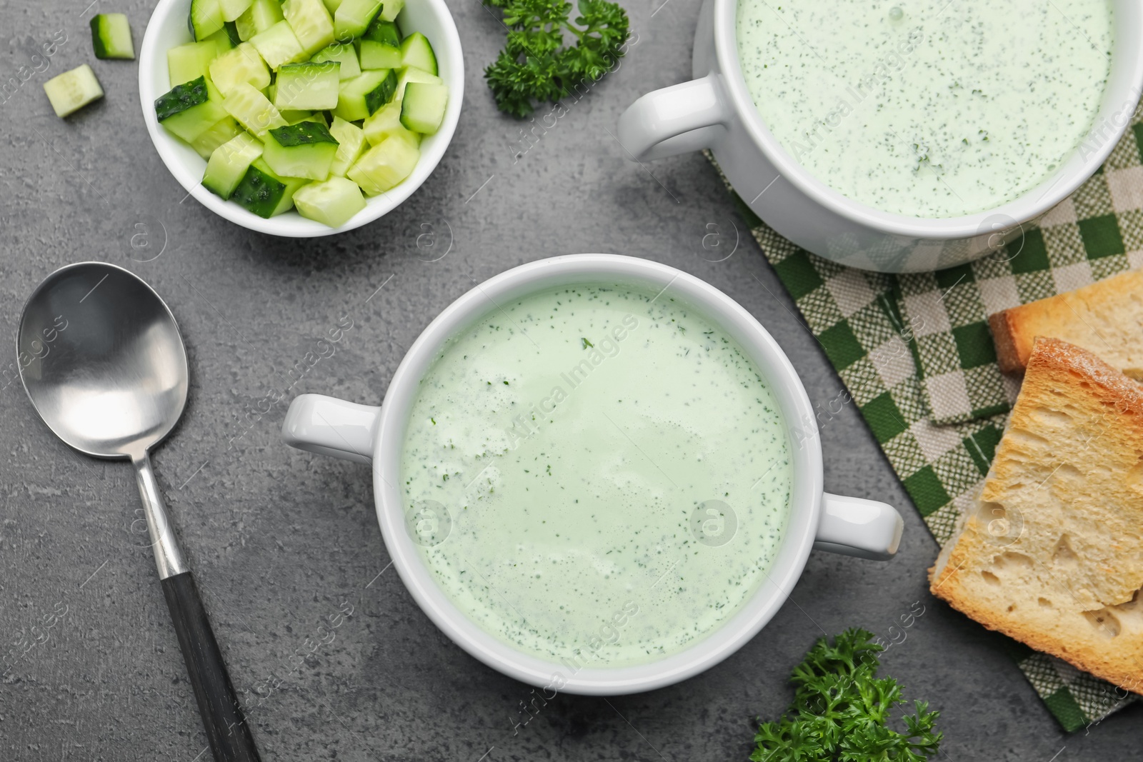 Photo of Tasty cucumber soup served on grey table, flat lay
