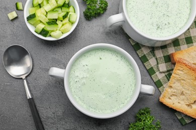 Photo of Tasty cucumber soup served on grey table, flat lay