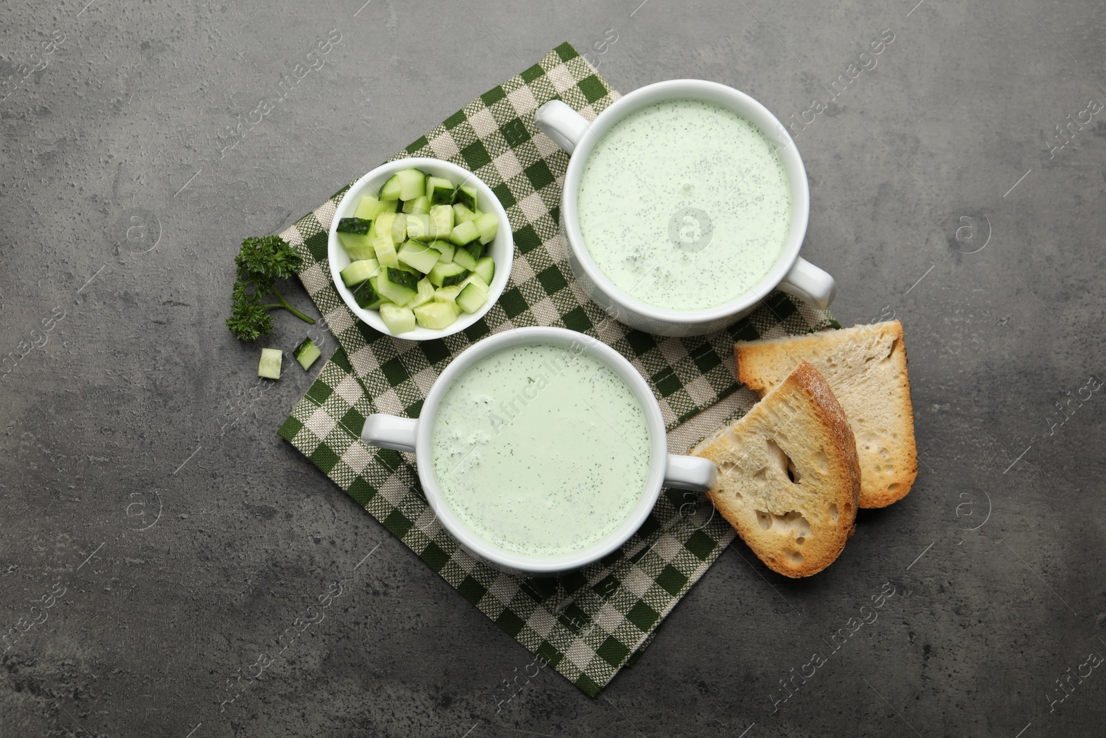 Photo of Tasty cucumber soup served on grey table, flat lay
